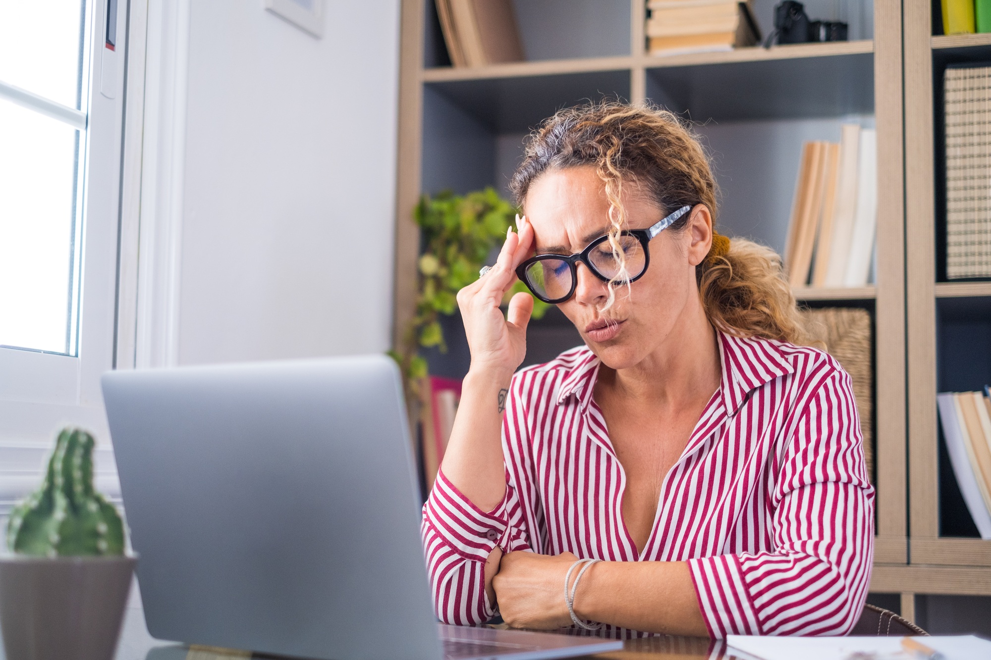 Unhealthy stressed businesswoman taking off eyeglasses, rubbing eyelids, suffering from dry eyes